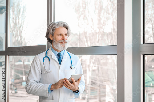 Senior male doctor with tab...
