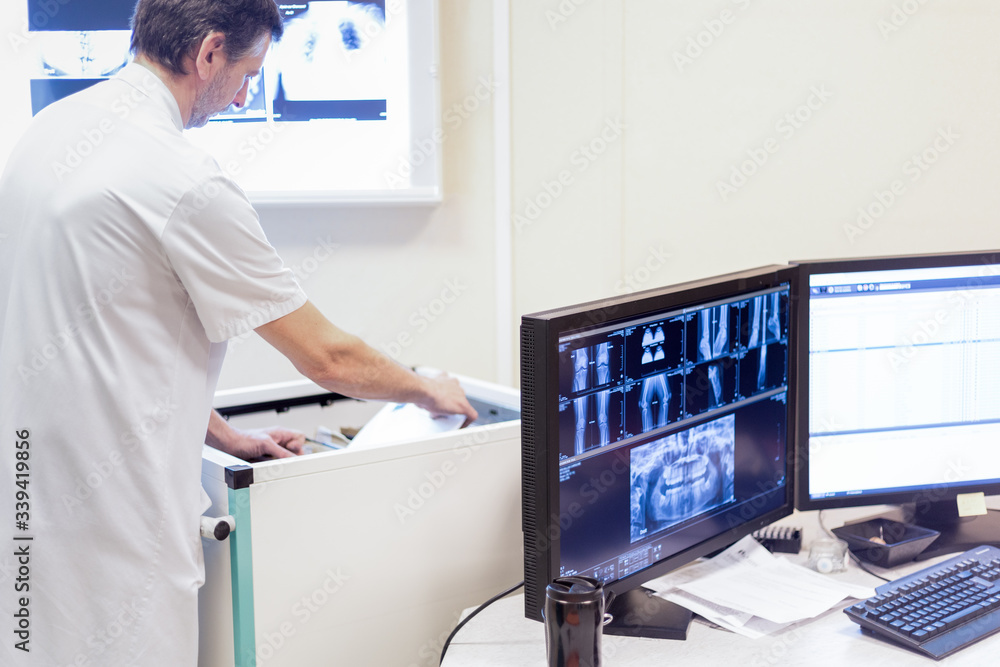 Médecin radiologue recherche dossier au bureau avec écran radio