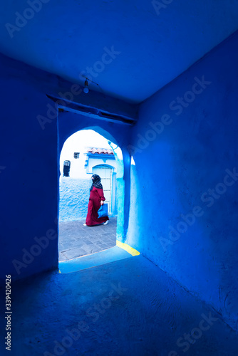 A traditional dressed moroccan woman walks in the old town (medina) of Chefchaouen in Morocco.. Social concept. © marcos