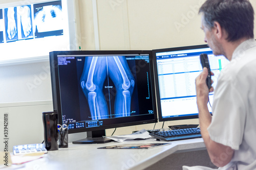 Médecin radiologue commente une radiographie sur écran au dictaphone photo
