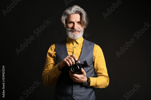 Handsome senior photographer on dark background