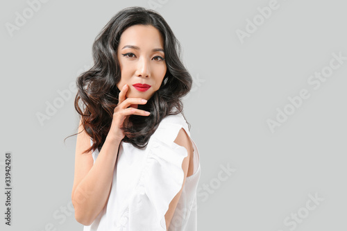 Young Asian woman with beautiful hair on grey background