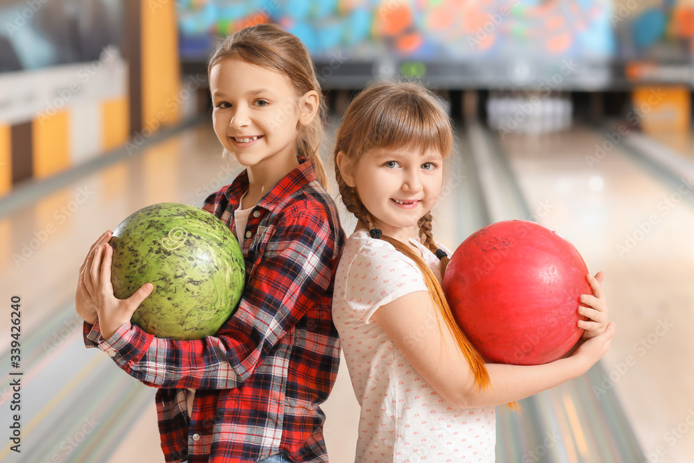 Fototapeta premium Little girls playing bowling in club