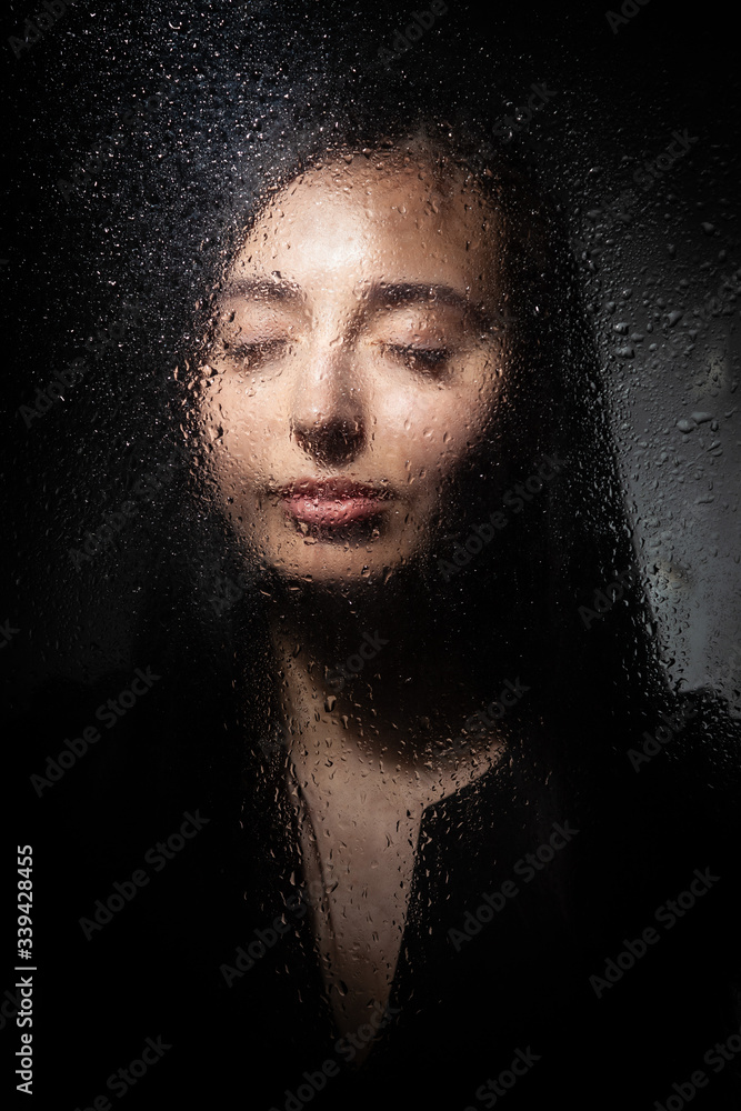 A slender brunette girl in a black dress stands on a gray background. A slender brunette girl in a black dress stands on a gray background.