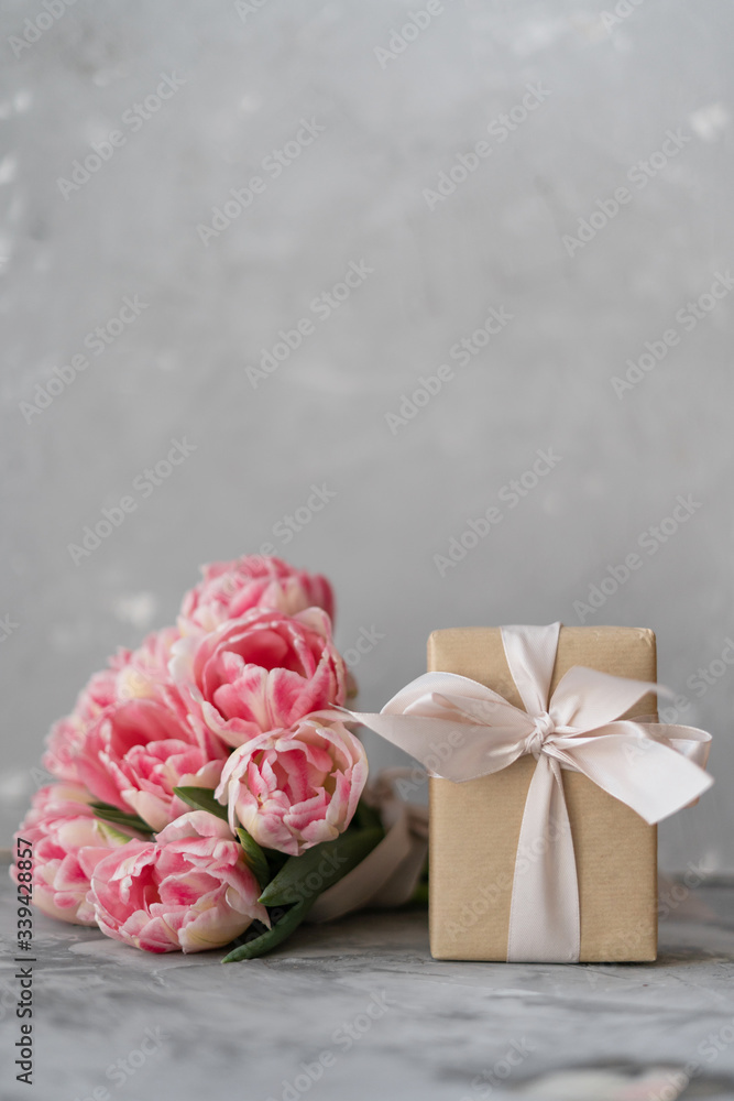 Bouquet of cut pink lilac tulips with a red gift box on gray checkered knitted background Bouquet of cut pink lilac tulips with a red gift box on gray checkered knitted background