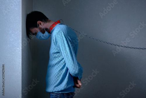 Принти на полотні man in medical mask, in a collar on a chain staying depressed in corner