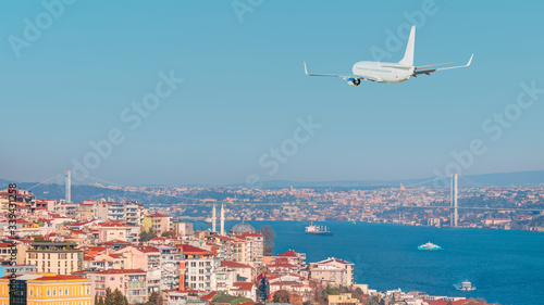 A passenger airplane is flying over istanbul city with blue Bosphorus sea and bridge