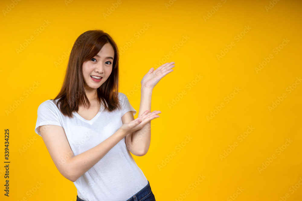 Young elegant Asian woman smiling and pointing to empty copy space isolated on yellow background Young elegant Asian woman smiling and pointing to empty copy space isolated on yellow background