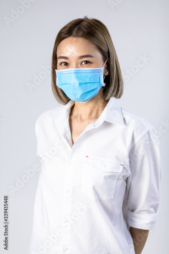 Studio portrait of Asian woman wearing face medical surgical mask, looking at camera, isolated on white background. Mask protection against virus. Covid-19, coronavirus pandemic © NVB Stocker
