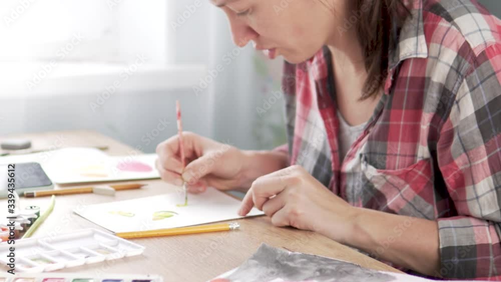 A woman paints lemon with watercolor paints. A woman paints lemon with watercolor paints.