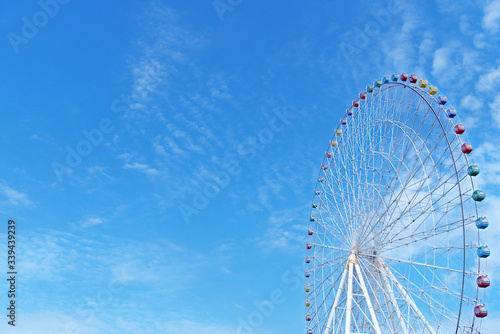 Ferris wheel in playground on summer sunny day with blue sky background