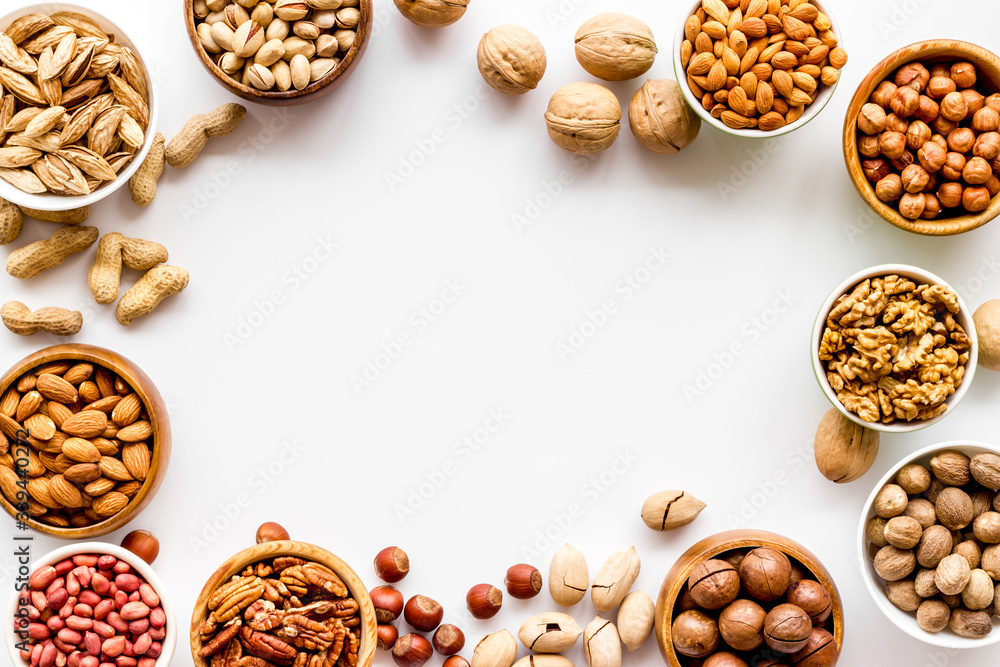 Fototapeta premium Nuts set in bowls on white background top-down frame copy space
