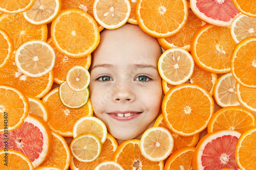 The face of a child is surrounded by oranges. The Importance and Need of Vitamin C for the Baby