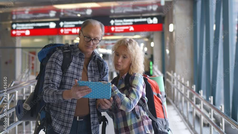 Senior couple of travelers reading on tablet pc in airport Senior couple of travelers reading on tablet pc in airport