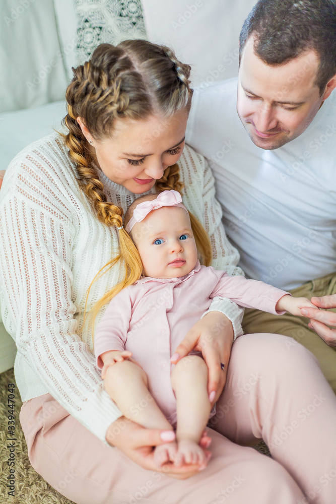 Beautiful young parents are holding their little newborn daughter in their arms. Blue-eyed little girl of 2 months. Baby Beautiful young parents are holding their little newborn daughter in their arms. Blue-eyed little girl of 2 months. Baby