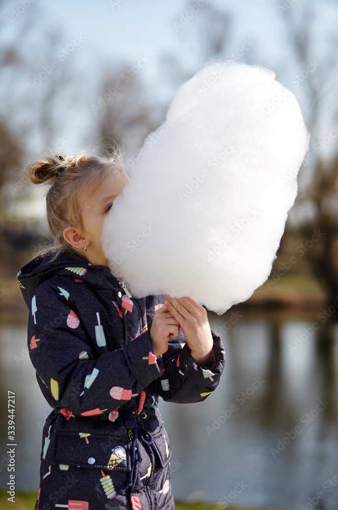 Cute little girl eating cotton candy