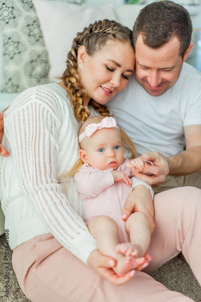 Beautiful young parents are holding their little newborn daughter in their arms. Blue-eyed little girl of 2 months. Baby Beautiful young parents are holding their little newborn daughter in their arms. Blue-eyed little girl of 2 months. Baby