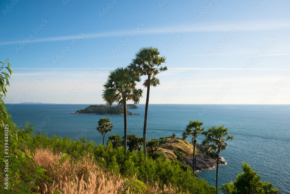 Beautiful tropical seascape with island view through exotic palm trees on a clear sunny day.