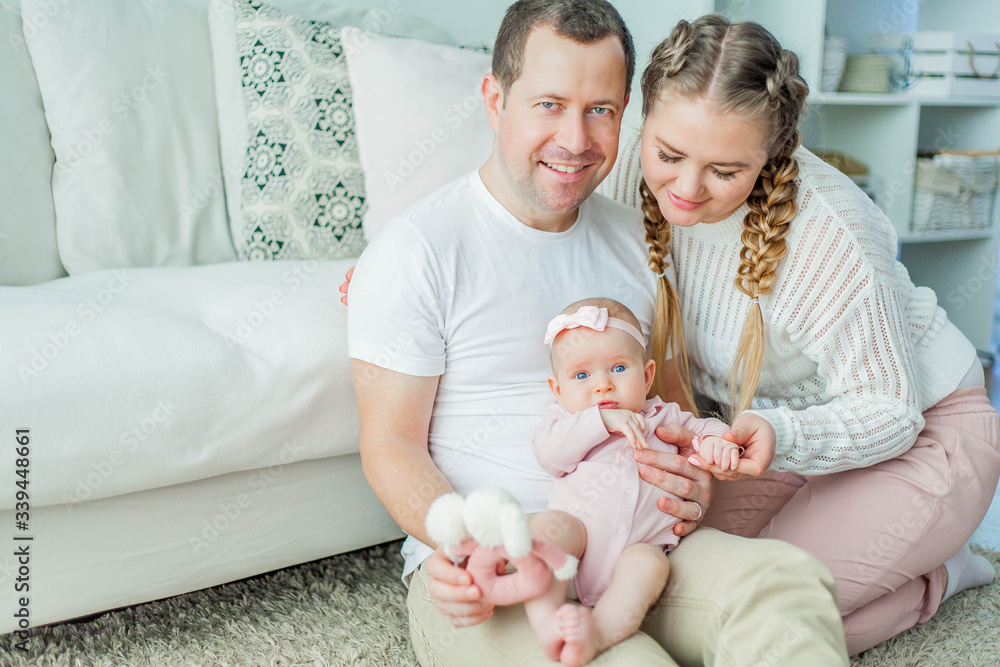 Beautiful young parents are holding their little newborn daughter in their arms. Blue-eyed little girl of 2 months. Baby Beautiful young parents are holding their little newborn daughter in their arms. Blue-eyed little girl of 2 months. Baby