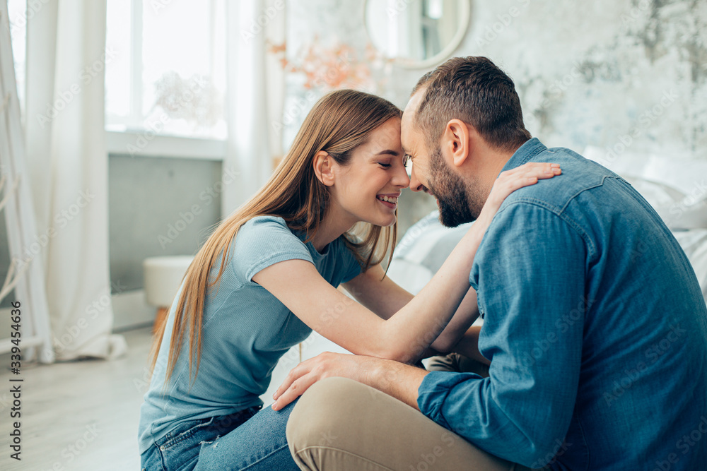 Romantic couple in the bedroom smiling and looking happy Romantic couple in the bedroom smiling and looking happy