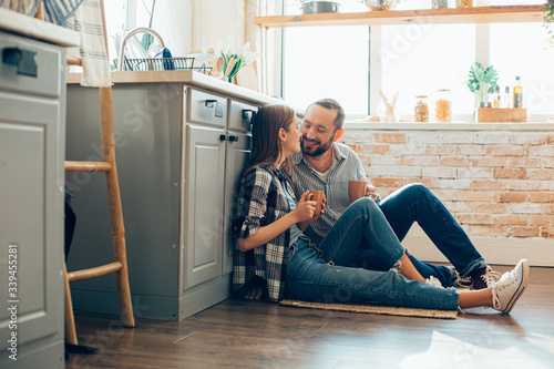 Relaxed couple sitting on the carpet with cups of tea stock photo