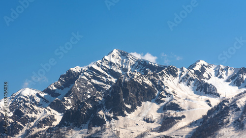 Beautiful snow-capped mountains against the blue sky in Sochi, Krasnodar territory, Krasnaya Polyana resort village, the Caucasus mountain range