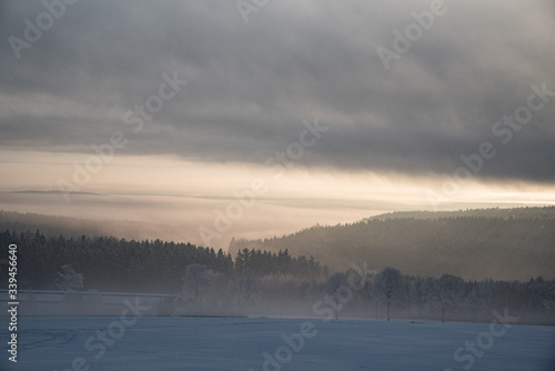 relaxing overcast moudy clouds in a winter valley while sunrise and sundown in a uphill winter scenery with field trees and forest