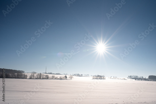 Feld im Winter mit Schneedecke, Sonnenschein und blauem Himmel © kennypool