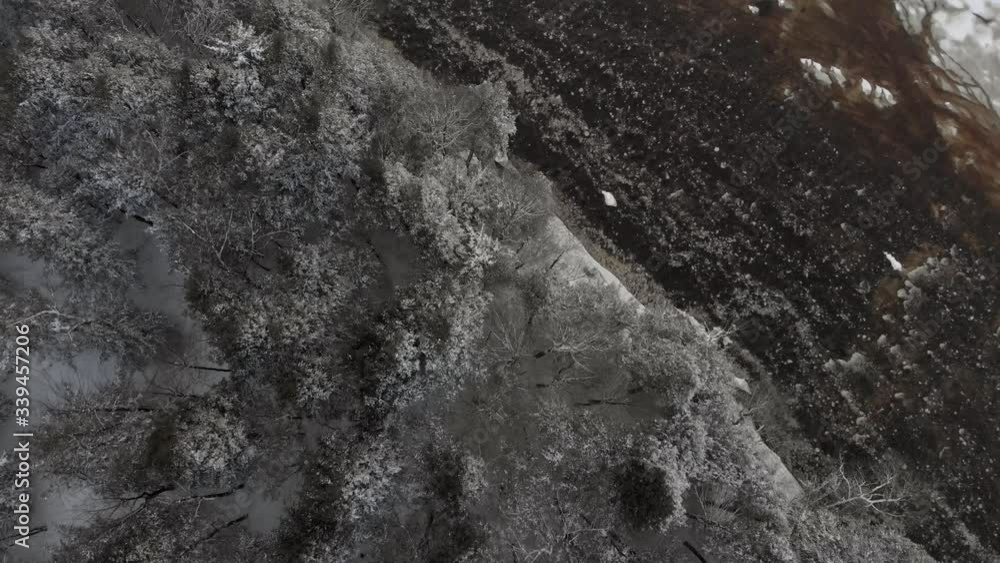 Drone crossing over a river to snowy trees in Drummondville Quebec Canada in winter Drone crossing over a river to snowy trees in Drummondville Quebec Canada in winter