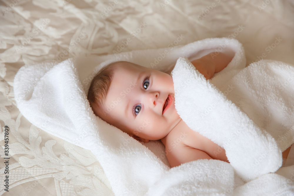 baby is wearing diapers and a white towel in bedroom. A newborn baby is resting in bed after a bath or shower. Children's room. Textiles and bedding for children. baby is wearing diapers and a white towel in bedroom. A newborn baby is resting in bed after a bath or shower. Children's room. Textiles and bedding for children.