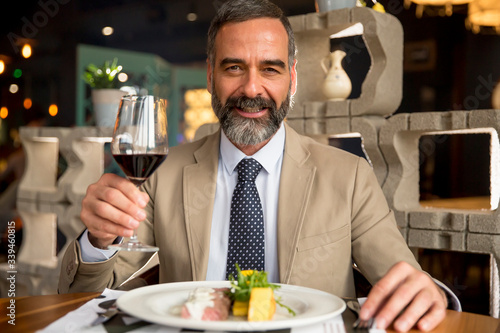 Handsome mature man drinking red wine during lunch