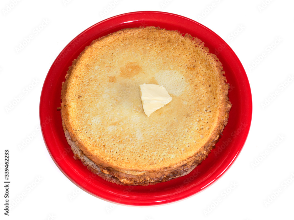 Staple of wheat golden yeast pancakes or crepes on red plate on a white background closeup Staple of wheat golden yeast pancakes or crepes on red plate on a white background closeup