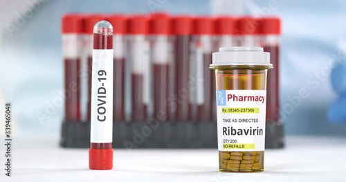 Lab tube with COVID-19 test and prescription bottle with ribavirin generic pills on the table photo