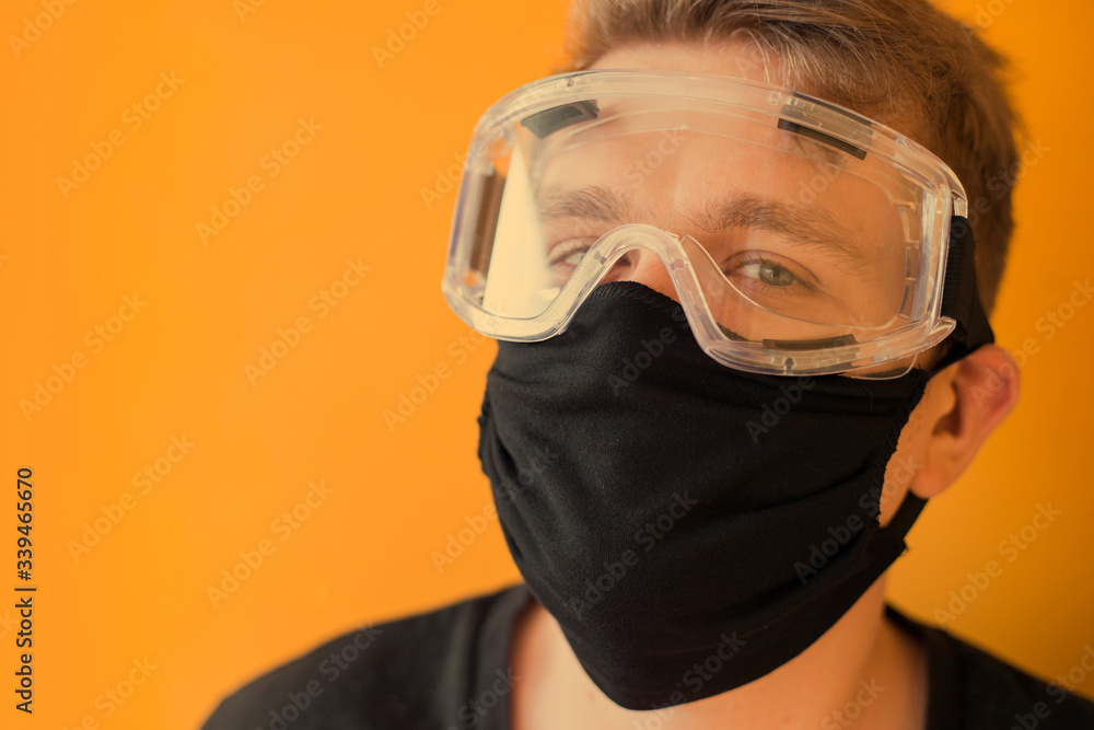 Man in protective glasses, medical mask on yellow background. Way to protect against coronavirus. Covid-2019, Pandemic 2020 concept Man in protective glasses, medical mask on yellow background. Way to protect against coronavirus. Covid-2019, Pandemic 2020 concept