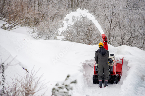 Worker cleaning or removing the snow winter by a snowblower. Snow removal equipment. Heavy precipitation and snow piles