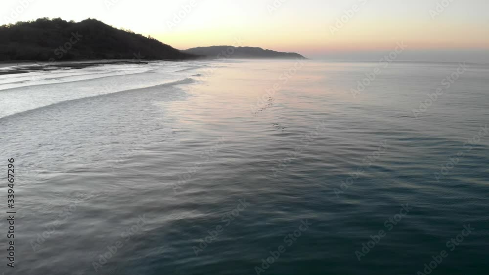 Smooth Waves with birds On Costa Rica Beach With A Beautiful Sunset On The Background.- aerial drone shot Smooth Waves with birds On Costa Rica Beach With A Beautiful Sunset On The Background.- aerial drone shot