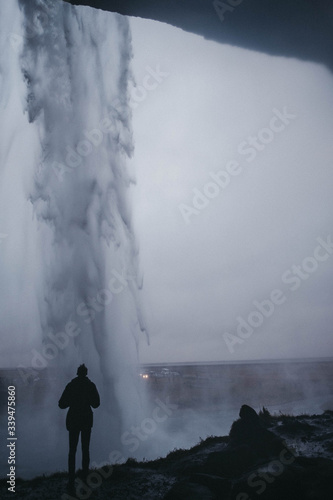 Tourist watching Seljalandsfoss waterfall from beneath, Iceland