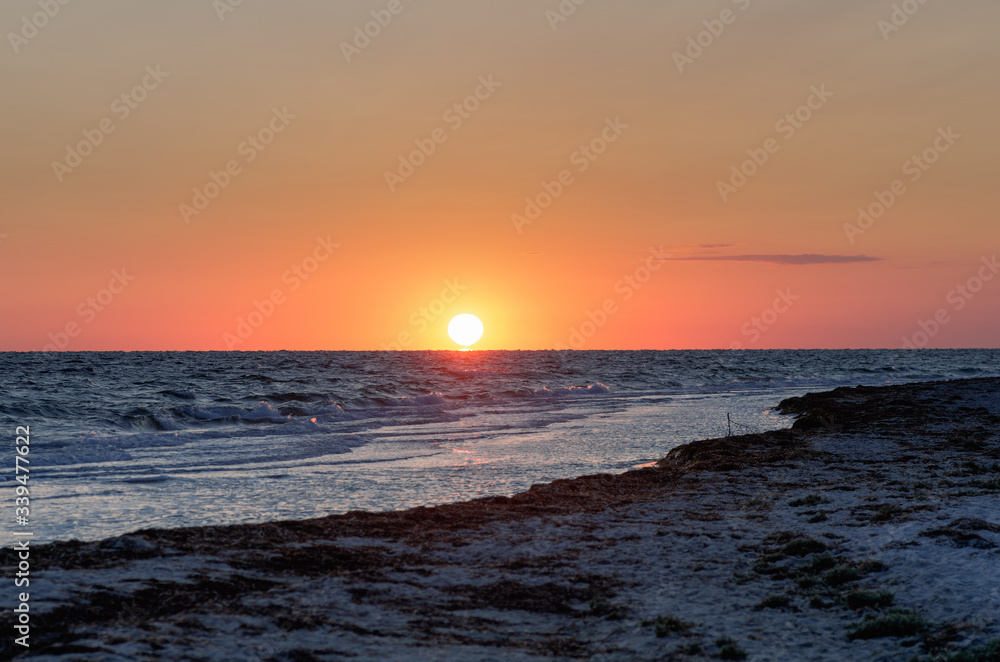 Obraz premium sea with waves and big bright sun over the horizon