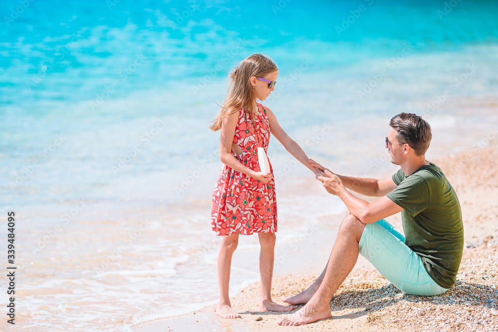 Young dad applying sun cream to daughter nose on the beach. Sun protection Young dad applying sun cream to daughter nose on the beach. Sun protection