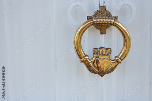 Fotografie Brass knocker with Irish Claddagh design on white painted door