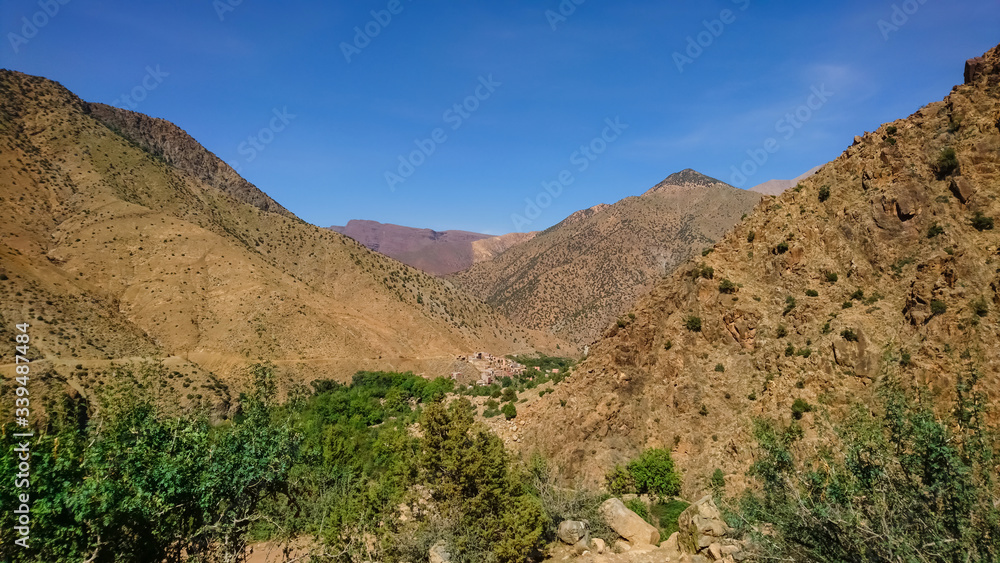 View of the Ourika Valley and a small village hidden between the mountains. Atlas mountains on a sunny day. View of the Ourika Valley and a small village hidden between the mountains. Atlas mountains on a sunny day.