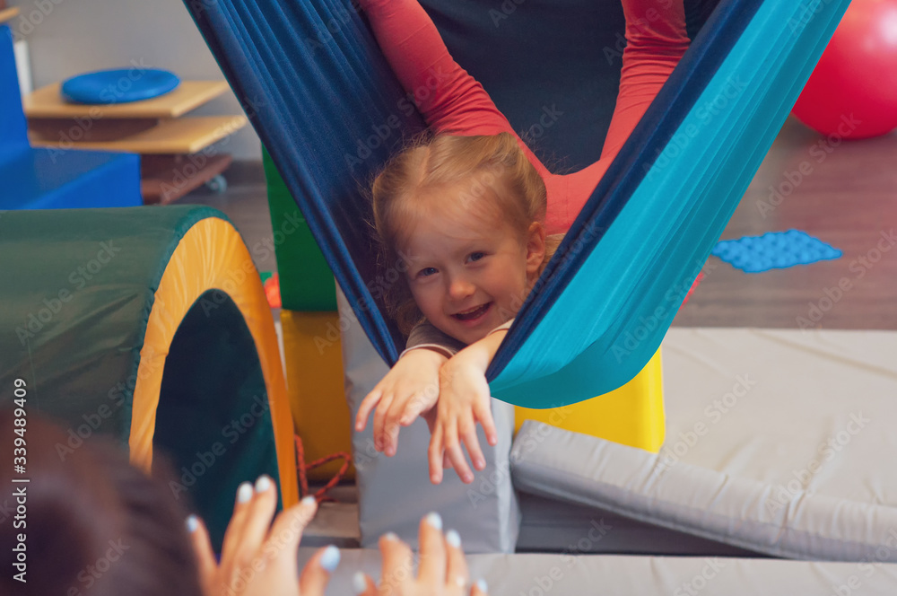 girl enjoying a sensory therapy on a hammock while physiotherapist assisting her