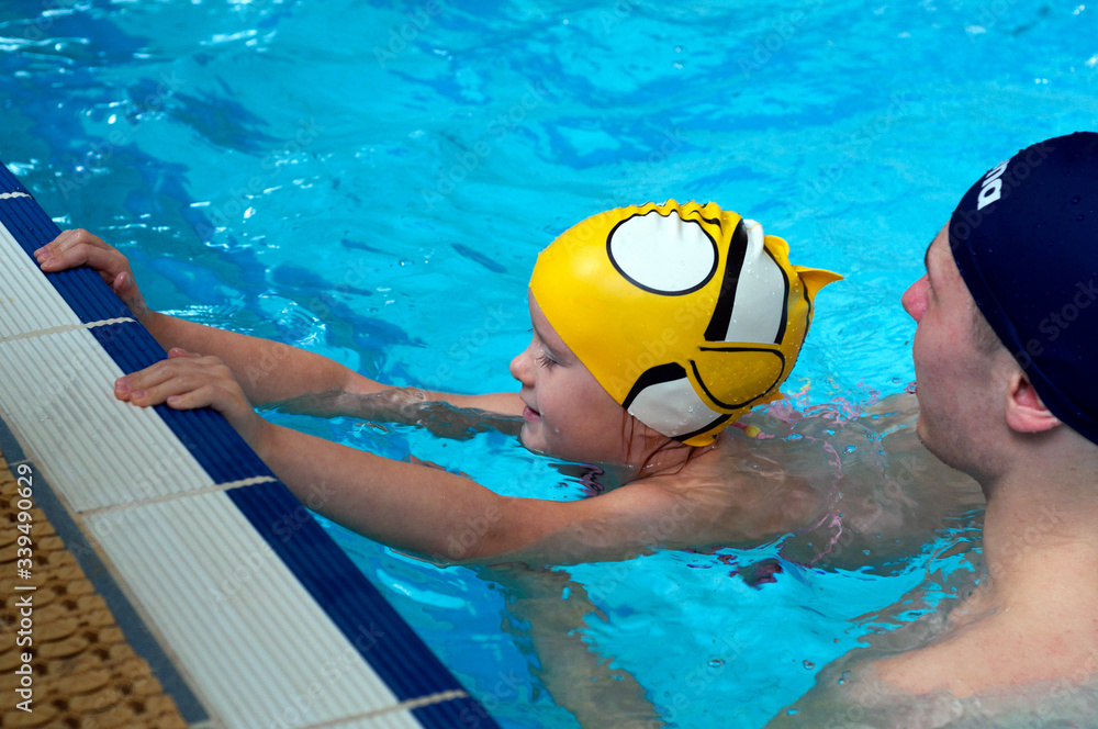 Swimming pool coach teaches a little girl to swim