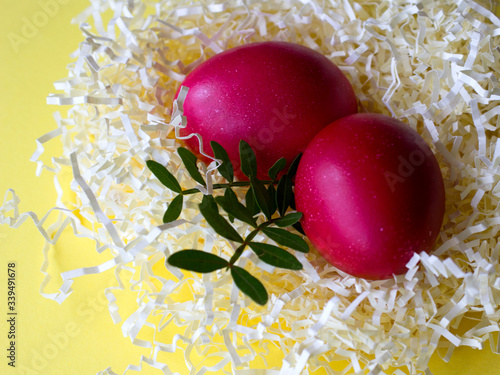 Colorful easter eggs in paper nest decorated with flower and leaves on yellow pastel background. Haapy easter! easter greeting card photo