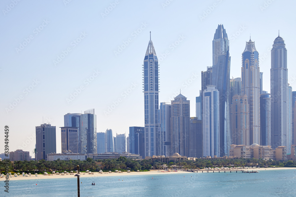 Obraz premium Dubai Marina skyscrapers with sea and beach in a sunny day, clear blue sky in Dubai