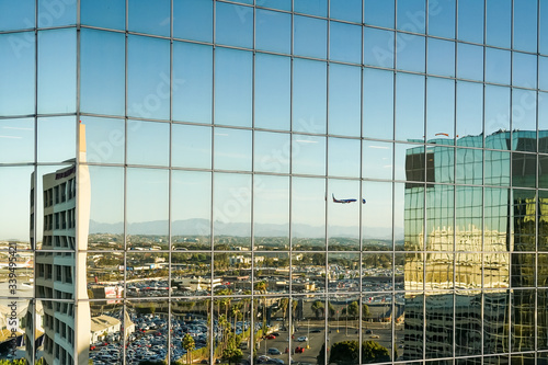 Landendes Flugzeug spiegelt sich in der  Glasfassade eines hohen Gebäudes © Richard