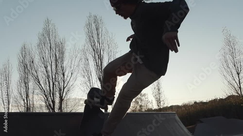 Skater does big air out of a quarter pipe  and grabs the board on a beautiful sunset session. Rides a streetboard, a cross between skateboard and snowboard photo