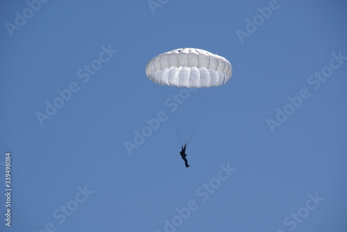 Close-up of a skydiver on a white parachute in a blue sky
