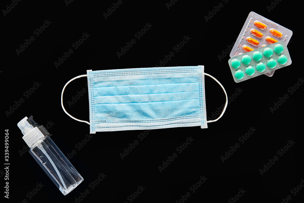 top view of medical mask, pills and hand sanitizer isolated on black top view of medical mask, pills and hand sanitizer isolated on black