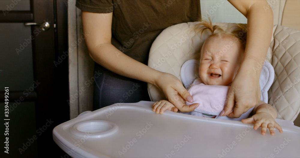 Caucasian baby crying while mother tries to feed it Caucasian baby crying while mother tries to feed it